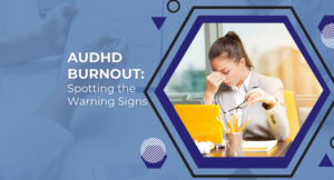 Blue banner with a hexagon frame showing a frustrated woman at a desk with a laptop; text reads 'ADHD Burnout: Spotting the Warning Signs'