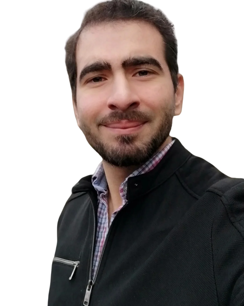 Portrait of a smiling man with dark hair and a short beard, wearing a black zip-up jacket over a plaid shirt, against a white background.