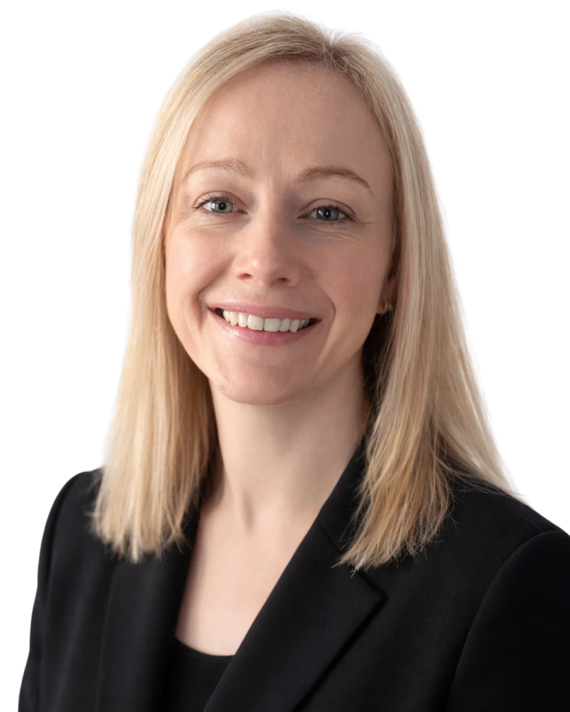 Professional headshot: smiling blonde woman in a black blazer facing the camera.