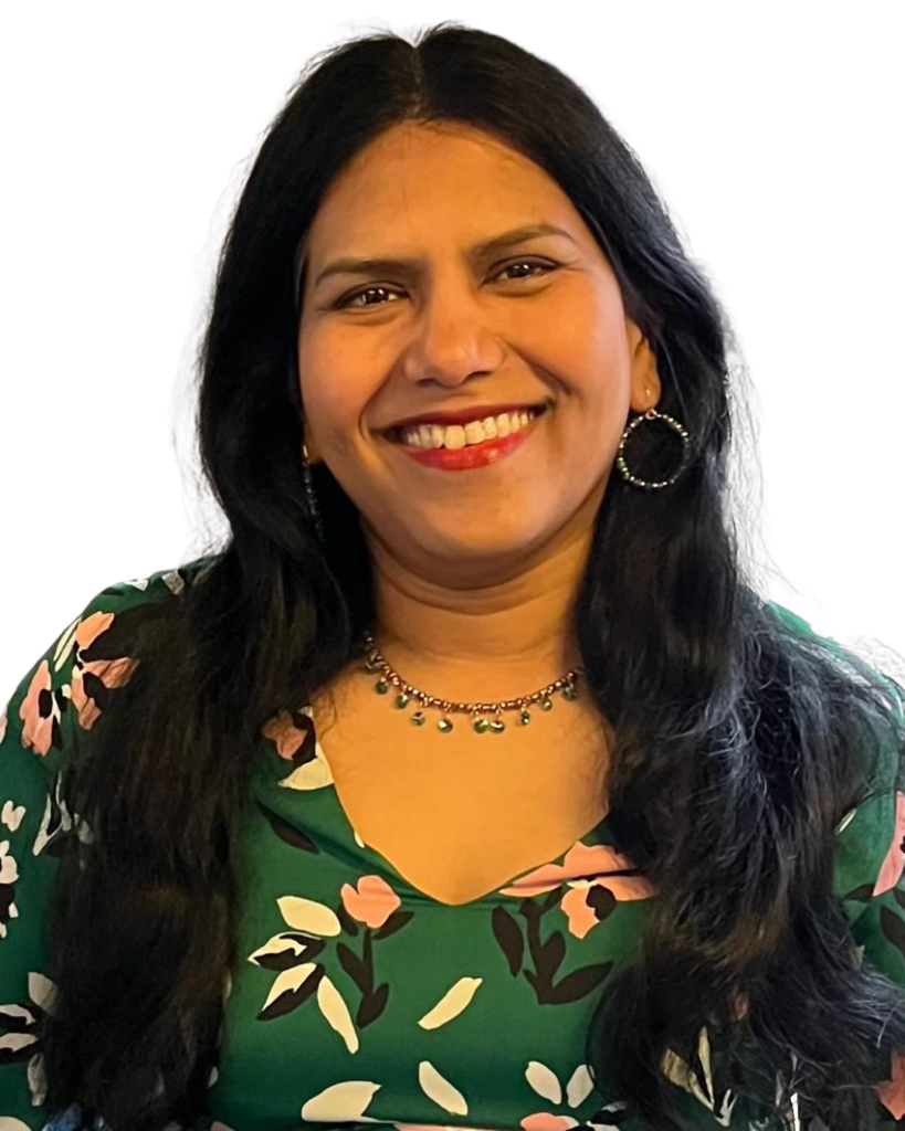 Smiling woman with long dark hair, wearing a green floral blouse and hoop earrings.