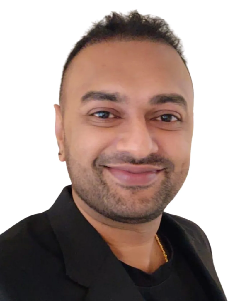 Smiling man with short dark hair and stubble, wearing a black blazer against a white background.