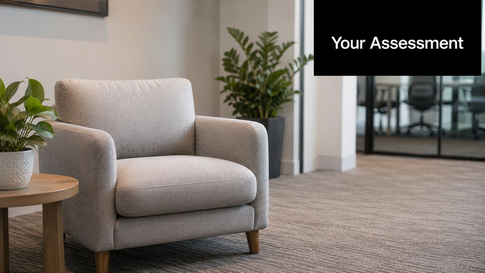 A comfortable gray armchair and a small side table with a plant in a modern office waiting area.